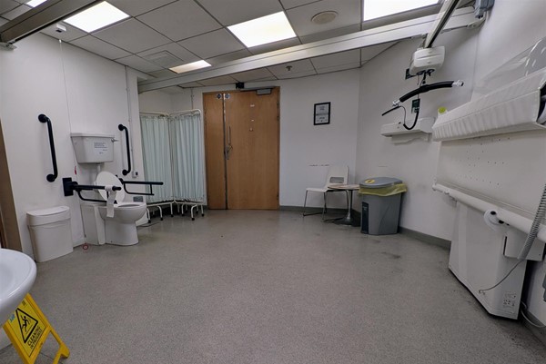 Image of very large accessible toilet with height-adjustable bench and ceiling hoist