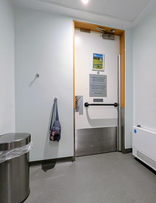 Image of door and coat hooks inside right-side transfer accessible toilet