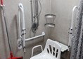 Accessible shower with fold down seat plus plastic moveable seat. There is a curtain around the shower area.