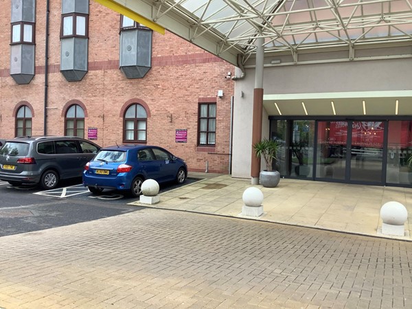 Picture of a hotel door with two cars parked to the left