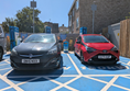 Image of a red car and a black car in a blue parkng space