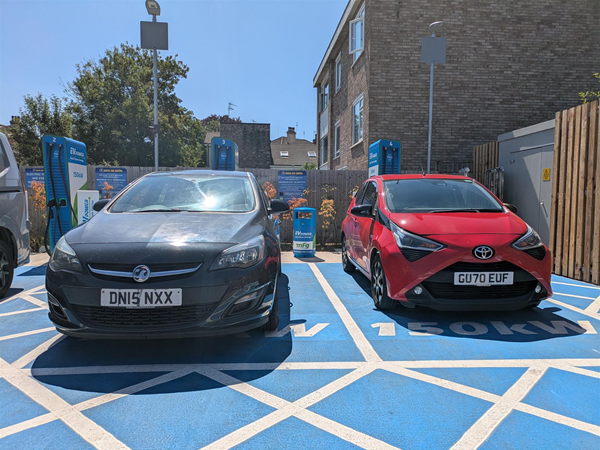 Image of a red car and a black car in a blue parkng space