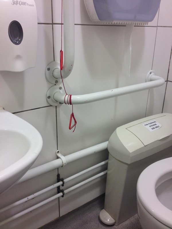 Red emergency cord tied up out of reach of anyone who falls to the floor and gets injured.