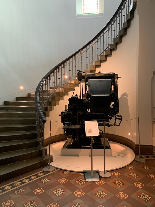 One of the staircases in the museum and an old printing press on display at the foot of the stairs