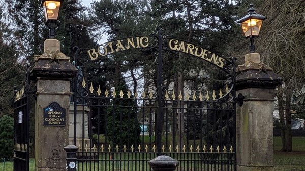 Image of entrance to the park, stone entry ways with black and gold fenching with the wording Botanic Gardens above.
