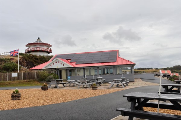 Consti Cafe with well tarmacked paths around it and wooden picnic benches