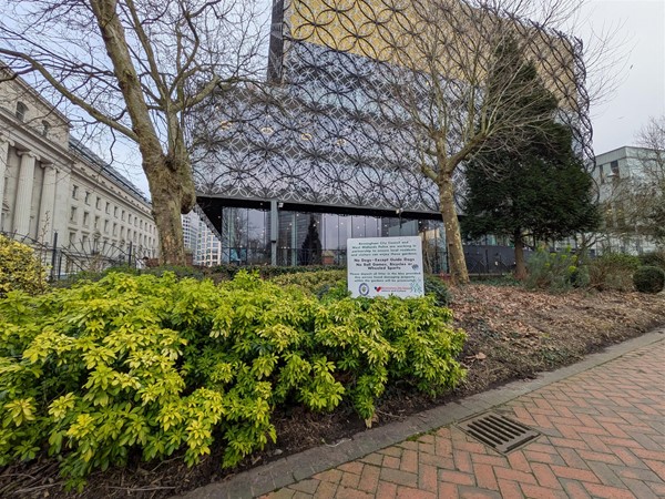 Image of a walkway in the park with the library in the background