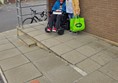 Two people at the top of an access ramp, one person in a powerchair.