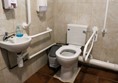 Toilet with grab rails and sink next to it