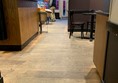 Image of the shop floor from the perspective of coming out of the toilet. There is space between the counter and tables of the shop but a narrow part where a wall sticks out.