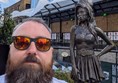 Image of Joe, a white man with short hair and a brown beard with the statue in the background.