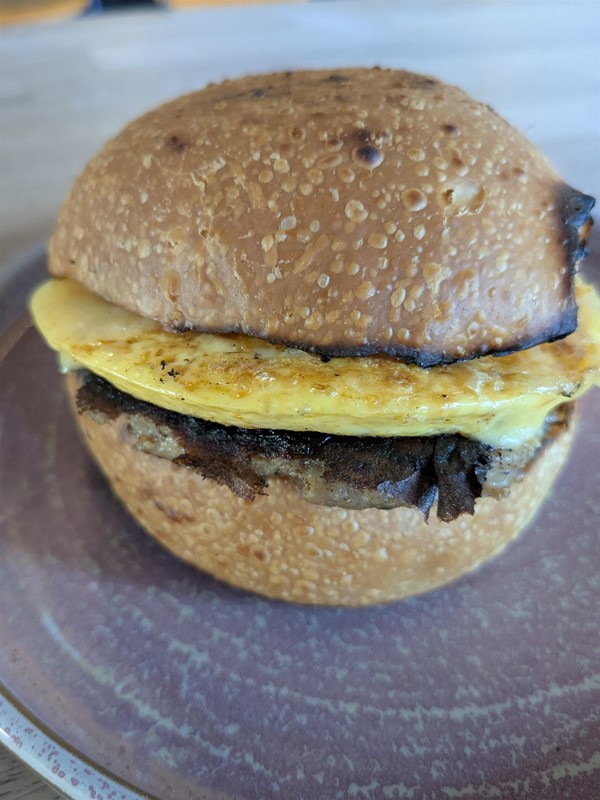 Image of a sausage and omelette bap on a blue plate