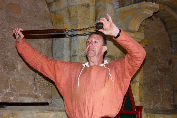 Man in period costume, holding a flail (hard spiky ball on a chain)