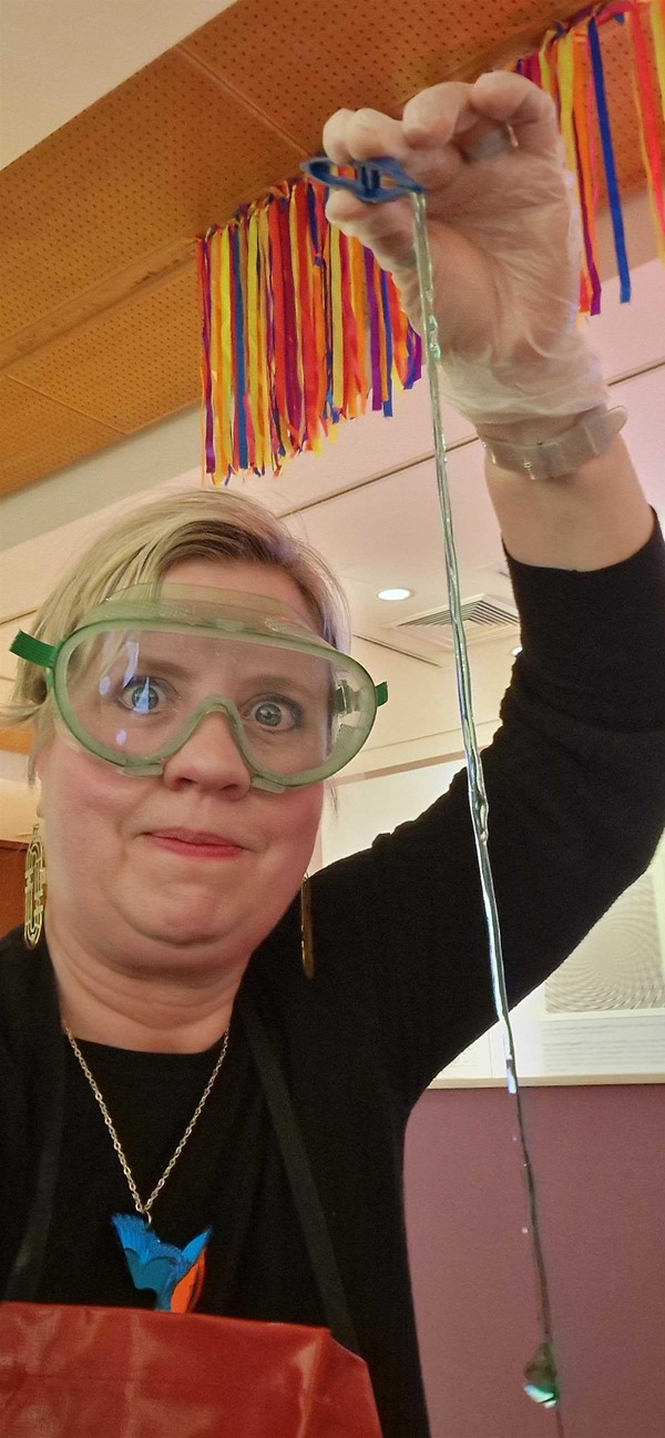 Middle aged woman wearing science safety kit, making gummy worms and slime.