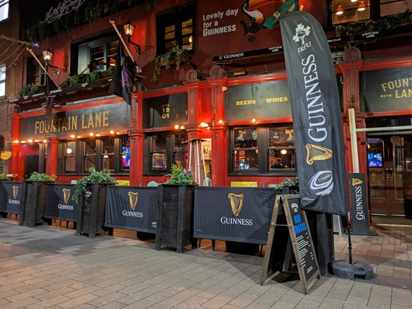 Image of entrance to Fountain Lane. Two large Guinness Rugby flags sit on either side of the doorway
