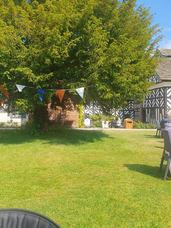 Lawn, tree with bunting and Little Moreton Hall in the background