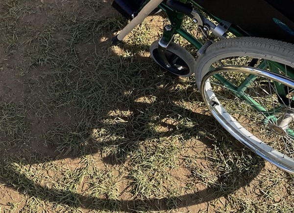 Image of a wheelchair wheel on  dirt path.