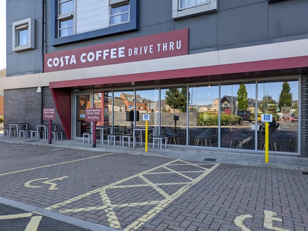 Image of entrance to Costa from outside, there are two accessible parking spaces
