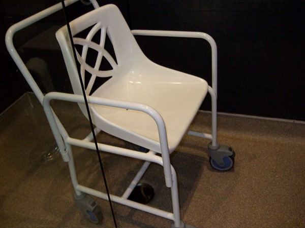 Shower chair that can be removed if non-disabled people in room. Note 4 wheels and arms that can be detached.