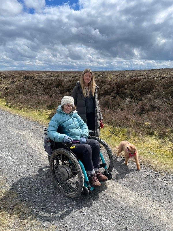 A person in a wheelchair with a dog on a road