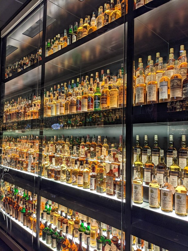 Loads of bottles of whisky in a cabinet.