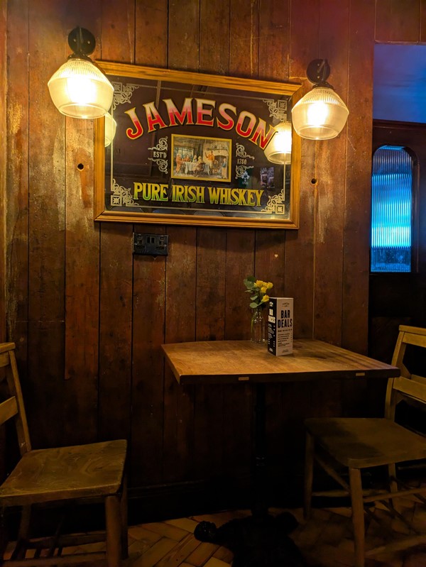 Image of seating in the bar, two wooden chairs and a small wooden table