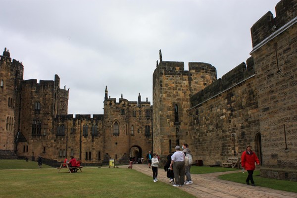 Castle walls with cobbled path running along the inside, and lawns next to it.