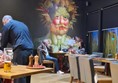 Photo is a colourful collage of a face made with veg painted on the wall of Cafe Corvina