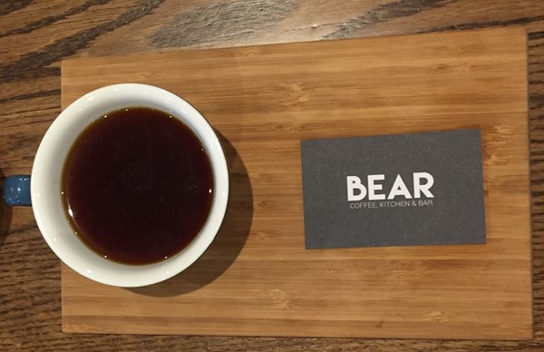 Aeropress coffee on wooden flight with Bear business card.