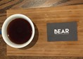 Aeropress coffee on wooden flight with Bear business card.