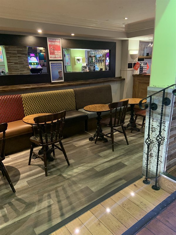 Image of a bar interior with small tables, seats an benches
