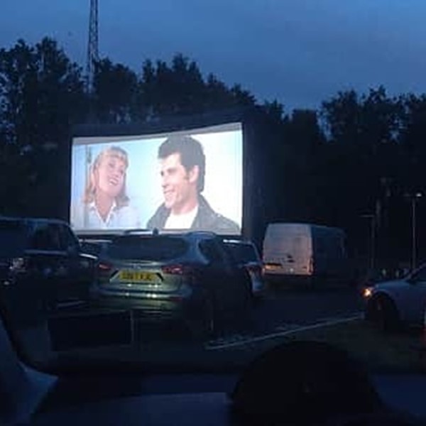 Drive in Movie screen with Grease on it. Scene has John Travolta and Olivia Newton John on it as Danny and Sandy