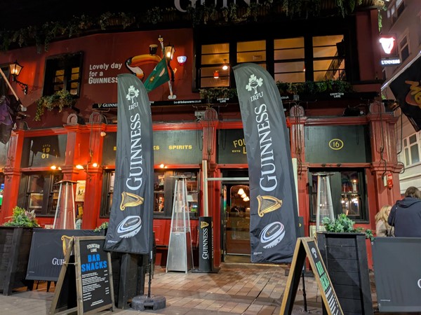 Image of entrance to Fountain Lane. Two large Guinness Rugby flags sit on either side of the doorway