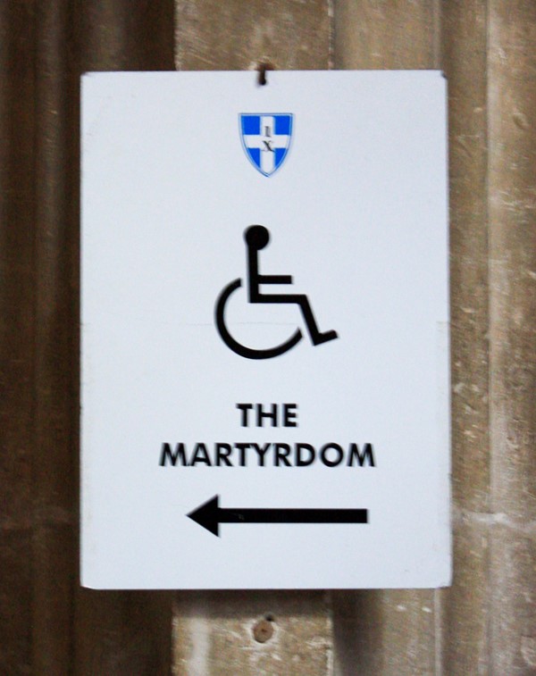 Sign with a wheelchair in the middle and the words the martyrdom underneath with an arrow pointing left.