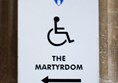 Sign with a wheelchair in the middle and the words the martyrdom underneath with an arrow pointing left.