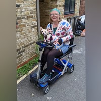 Woman on mobility scooter, dog on lap. Wearing matching jumpers.