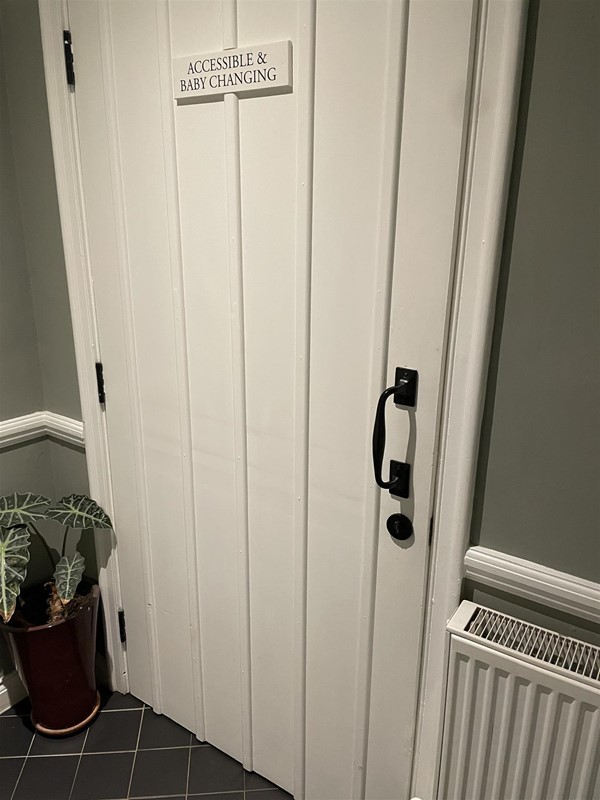 Image of a white door with accessible baby changing