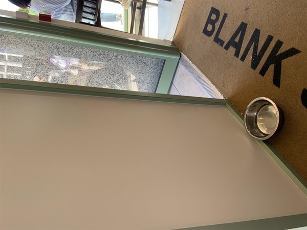 Image of  a metal dog bowl on the floor in between the two doors just inside the entrance.