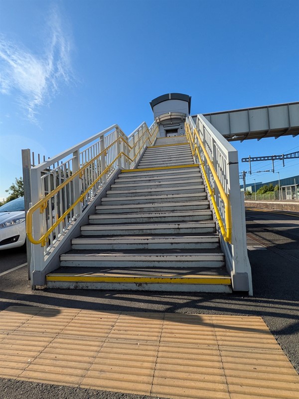 Image of of the foot of a stairway to the platform that crosses the tracks