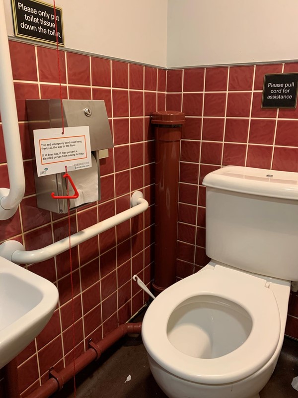 Closer image of toilet and red cord which has a Euan’s Guide red cord card on it
