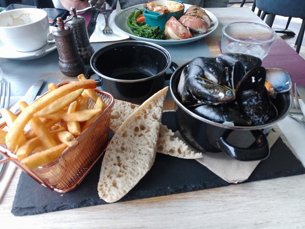 Half pot of mussels with fries and sourdough bread.