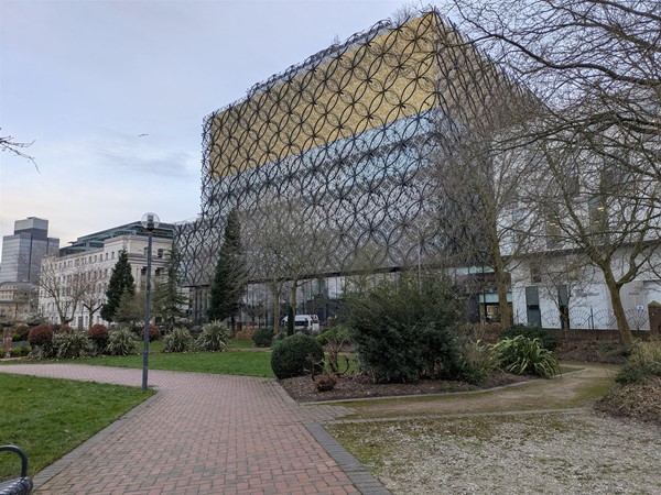 Image of a walkway in the park with the library in the background