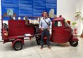 Image of a man standing next to an old red fire vehicle.