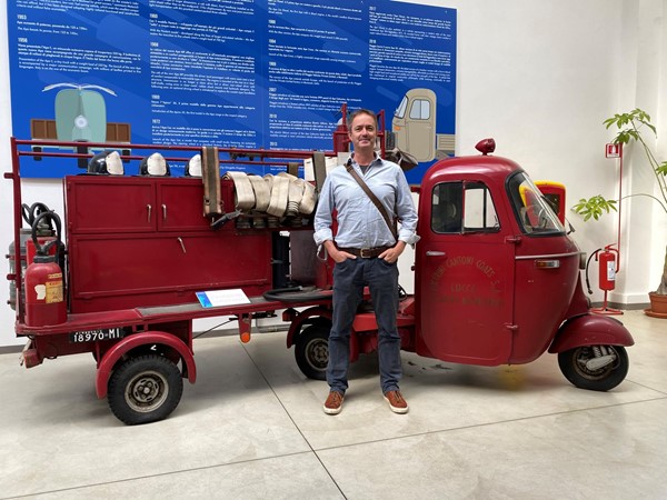 Image of a man standing next to an old red fire vehicle.