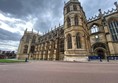 Outside photo showing part of the stone built castle complex in beautiful gothic style with flat smooth paths around it and a beautiful blue sky on a nice spring day