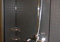 Shower with hand-held nozzle. Note support rail.