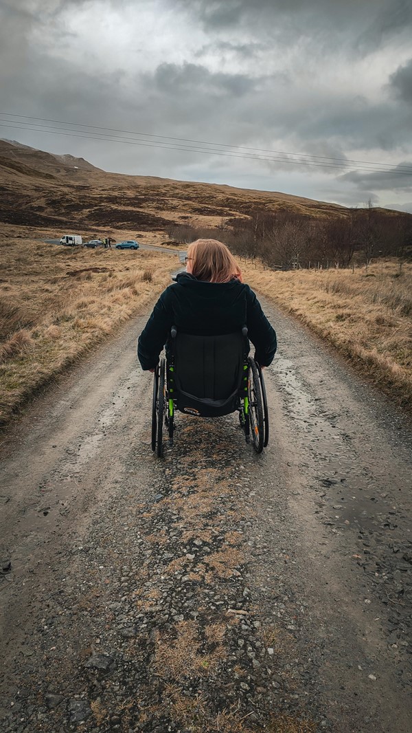 Helen wheeling along a road. This is the section of road near the the second parking area . It is uneven and a bit gravelly.