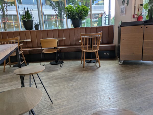 Image of wooden seats and a long leather bench along the wall, there are power sockets beneath the benches