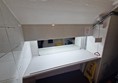 View of the changing table in the accessible toilet. This section would not be locked. A mirror is mounted above it, and the space is brightly lit. A red emergency cord with a Euan’s Guide red cord card hangs nearby.
