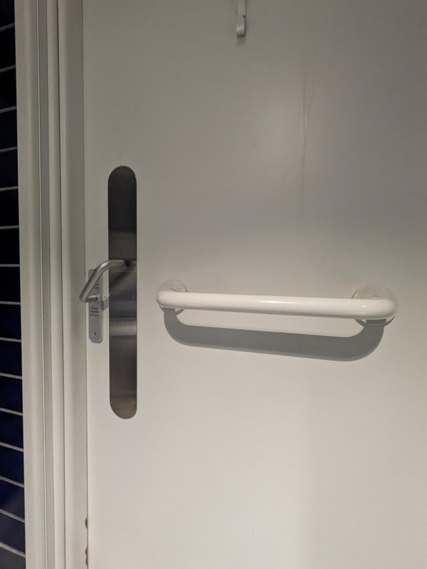 Image of the accessible toilet door with a grab rail
